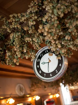 Ronde klok aan het met hop versierde plafond van de brasserie
